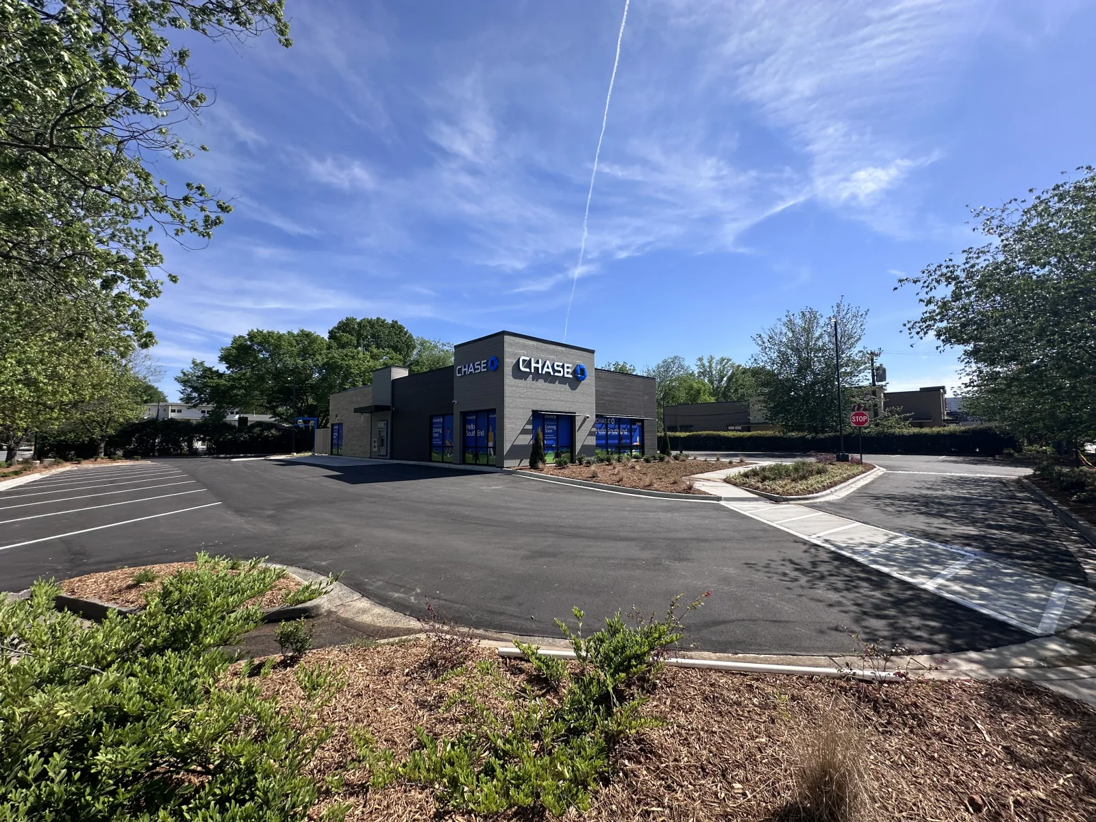 Newly paved asphalt parking lot with striping and landscaped borders at commercial building