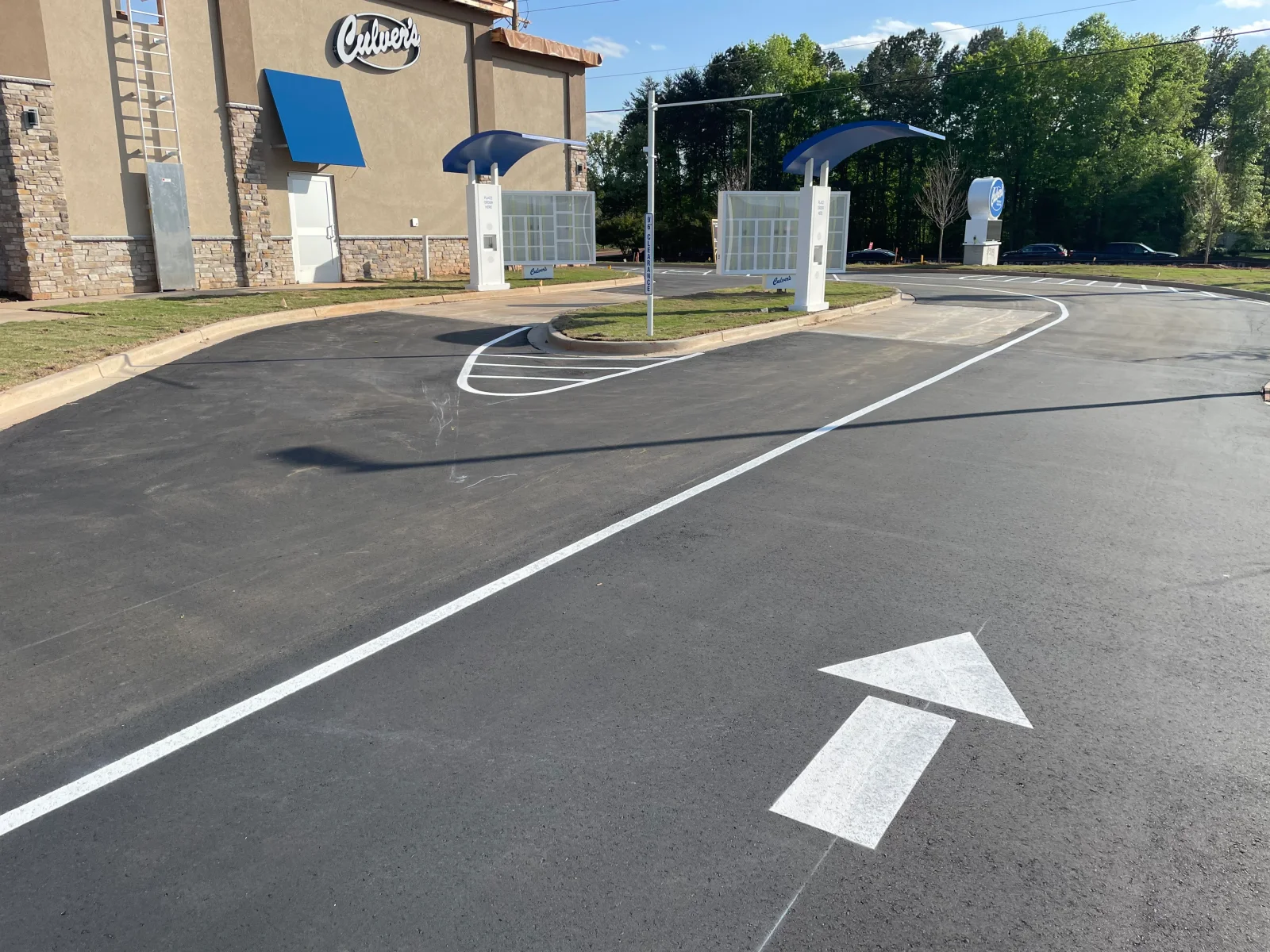 Newly paved asphalt drive-through with white directional arrows and lane markings