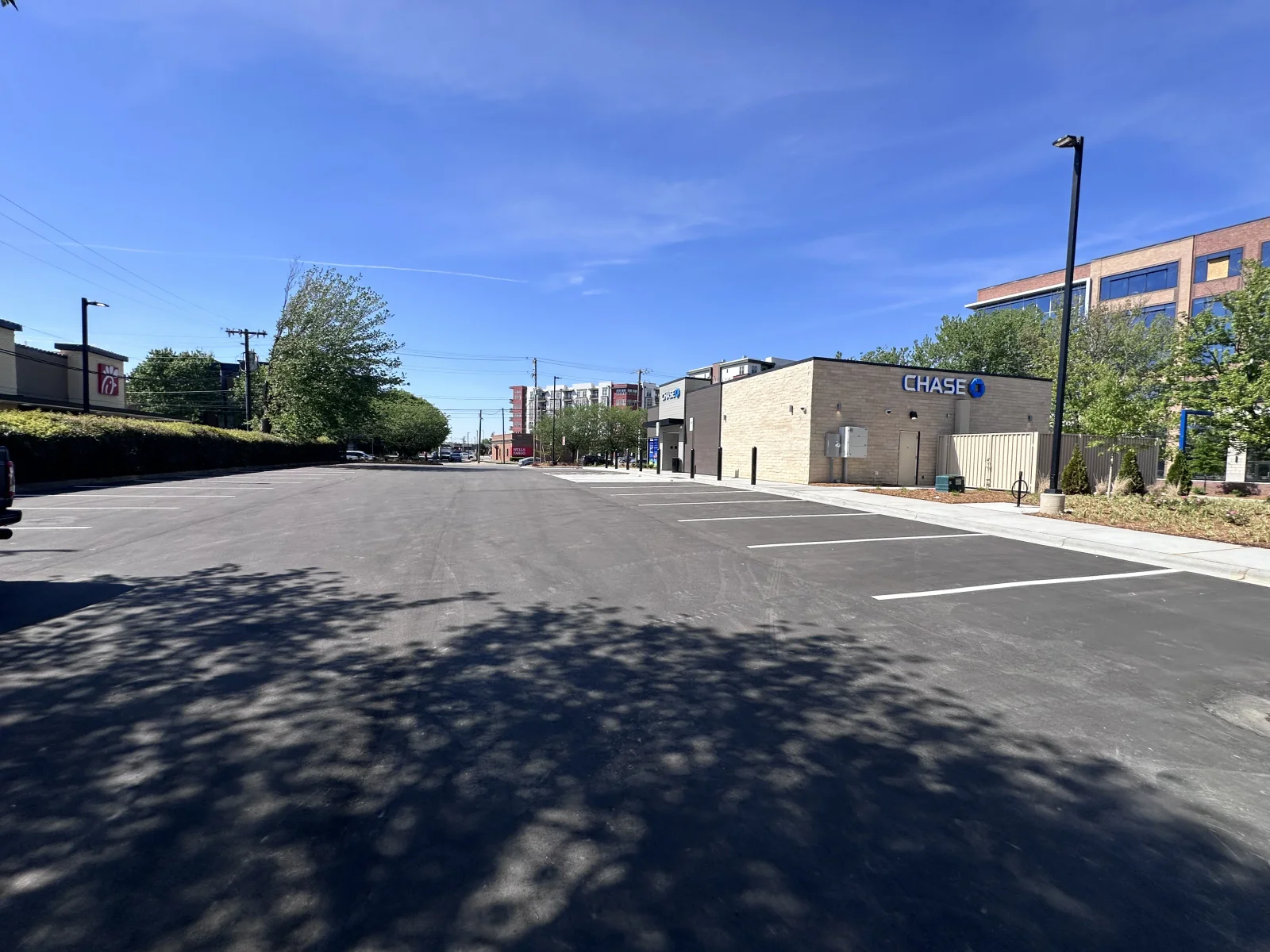 Newly paved asphalt parking lot with white striping and modern street lighting