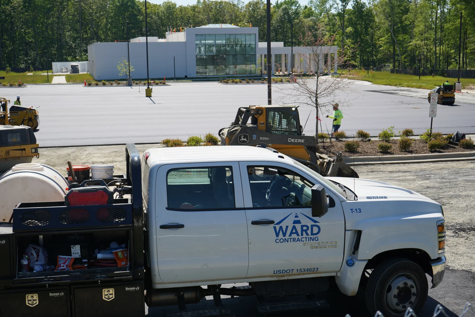Fresh asphalt paving with heavy equipment and crew on commercial parking lot