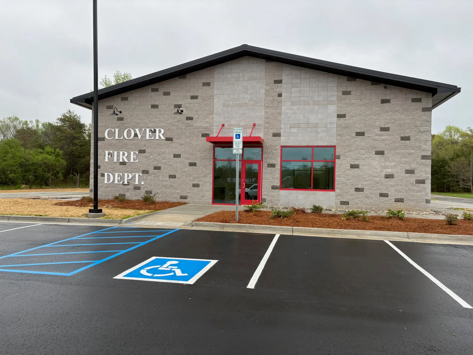 Asphalt parking lot with handicap spaces and white line markings in front of brick fire station