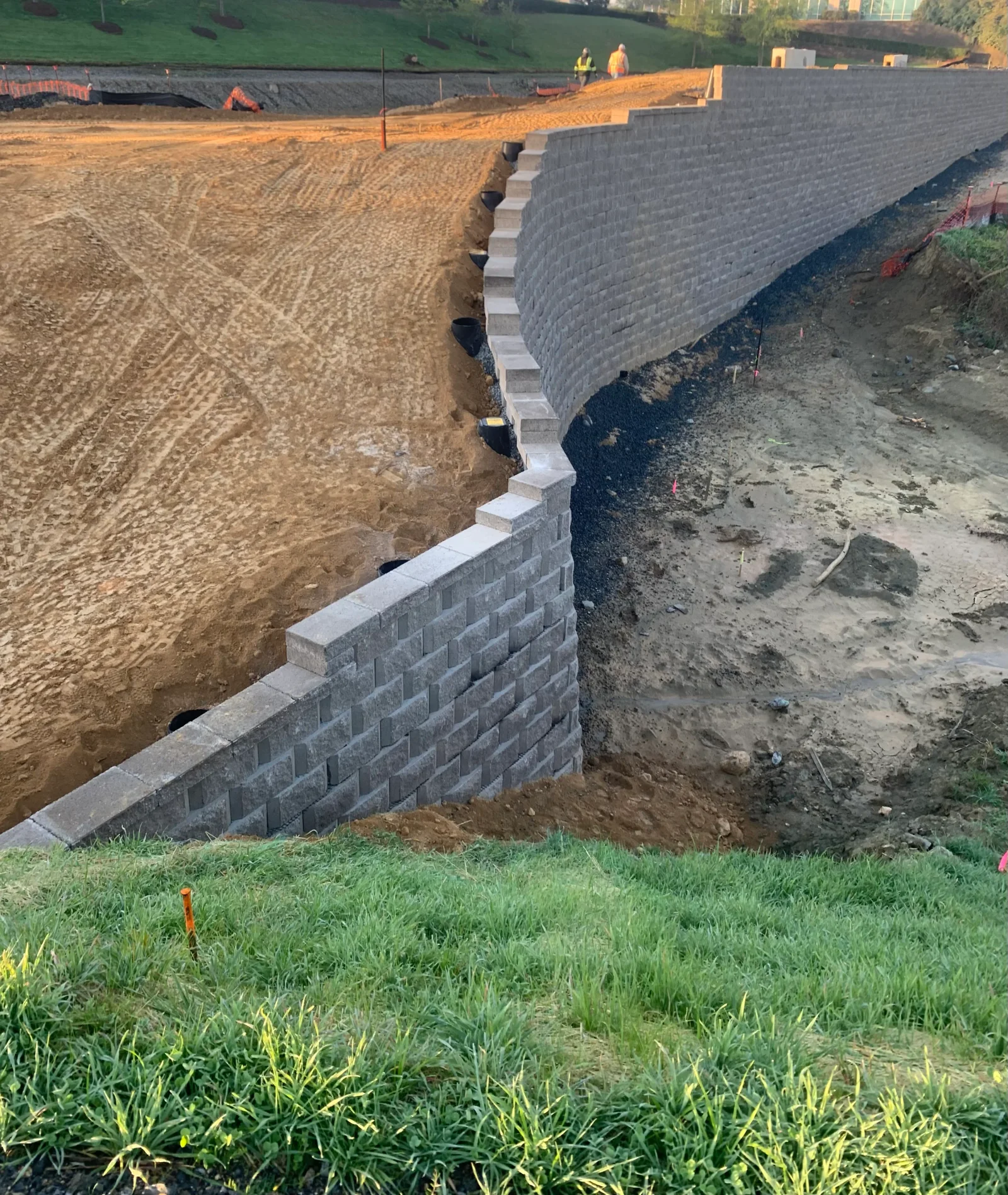 Gray segmental concrete retaining wall with stepped base on prepared soil subgrade