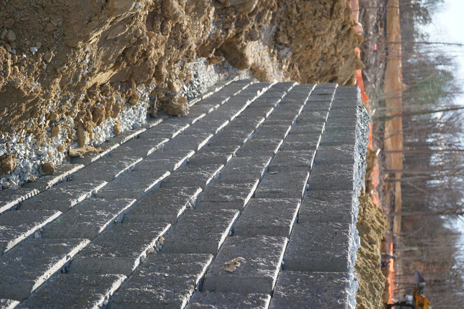 New asphalt driveway with white striping installed next to stone retaining wall