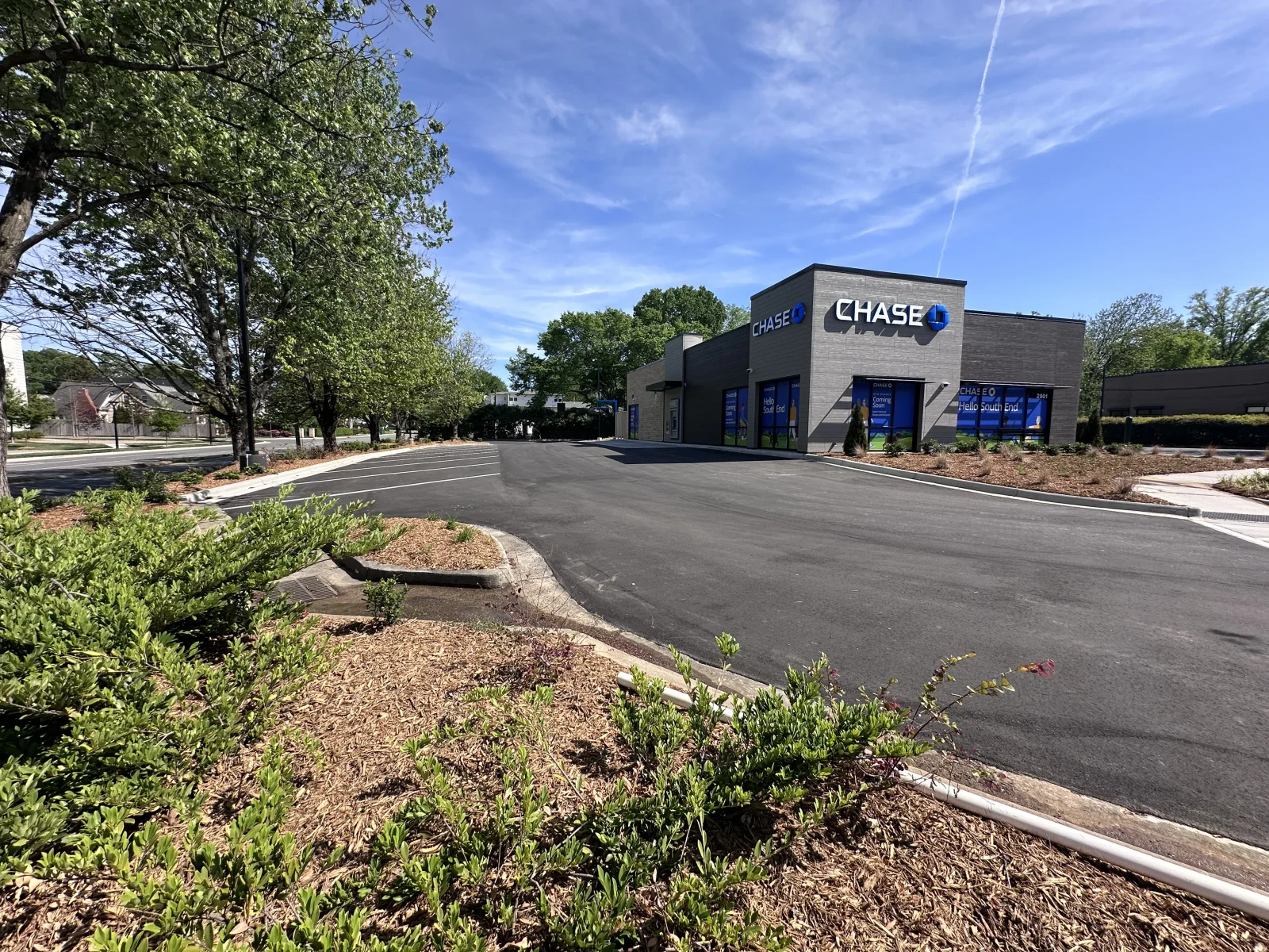 Newly paved black asphalt parking lot with metal edging and landscaped perimeter beds